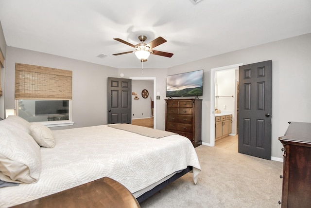 bedroom with light colored carpet, ensuite bath, and ceiling fan