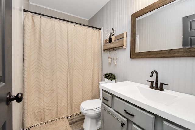 bathroom featuring wood-type flooring, vanity, toilet, and crown molding