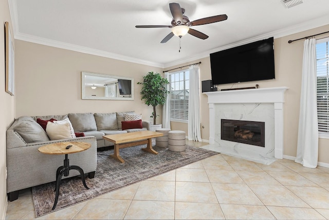 living room with crown molding, a high end fireplace, light tile patterned floors, and ceiling fan