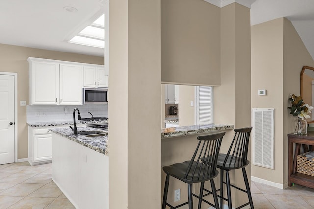 kitchen featuring stone countertops, white cabinetry, kitchen peninsula, and appliances with stainless steel finishes