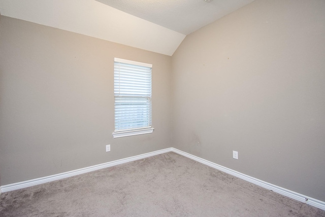 carpeted empty room with lofted ceiling