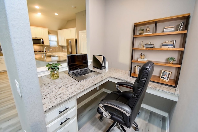 office area featuring sink, built in desk, vaulted ceiling, and light wood-type flooring