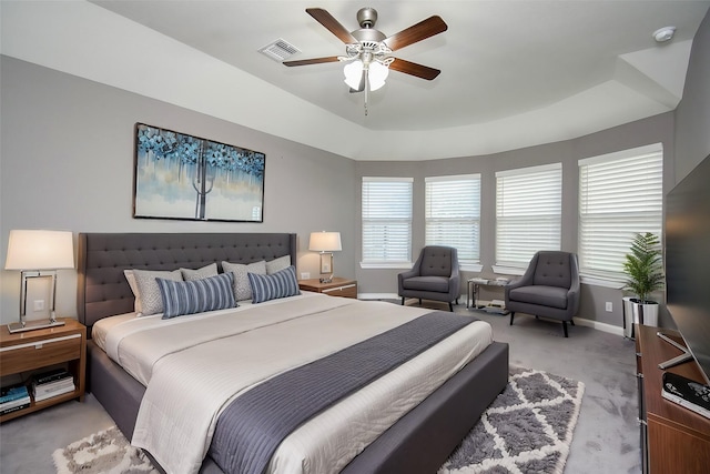 carpeted bedroom featuring a raised ceiling and ceiling fan