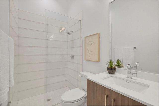 bathroom featuring vanity, toilet, and a tile shower