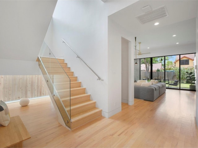 stairs featuring ceiling fan, hardwood / wood-style floors, and a wall of windows