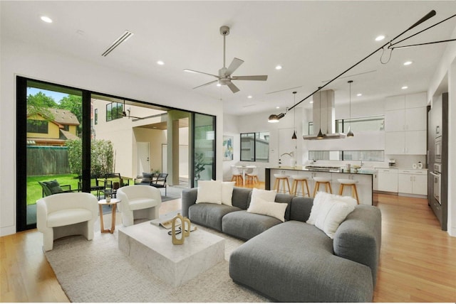 living room featuring a wealth of natural light, ceiling fan, and light wood-type flooring