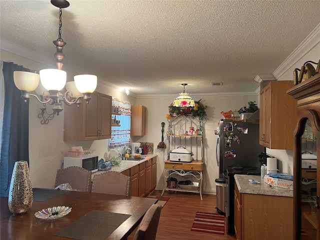 kitchen featuring sink, dark hardwood / wood-style floors, a notable chandelier, pendant lighting, and ornamental molding