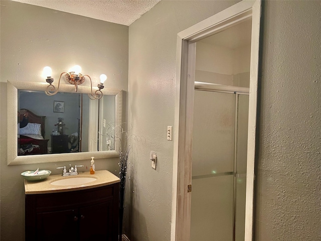 bathroom featuring vanity, a shower with shower door, and a textured ceiling