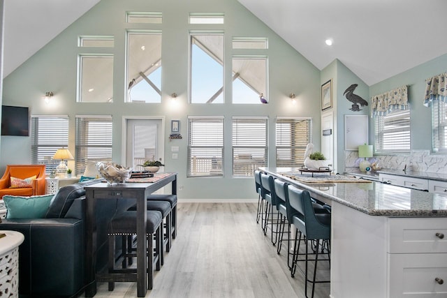 kitchen featuring white cabinets, a kitchen breakfast bar, light hardwood / wood-style floors, and light stone countertops