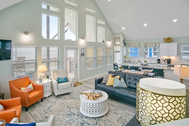 living room with high vaulted ceiling and light wood-type flooring