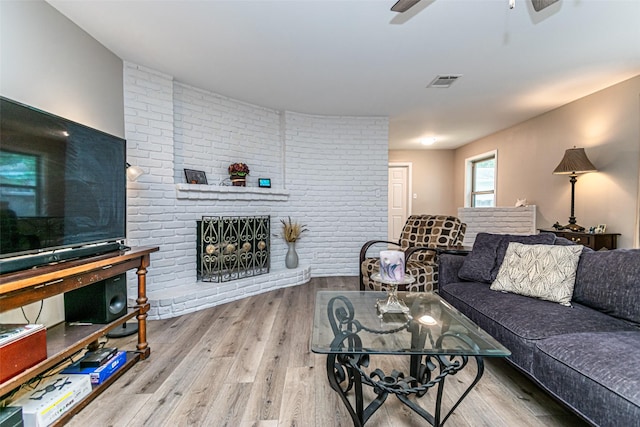 living room with hardwood / wood-style flooring, brick wall, and a brick fireplace