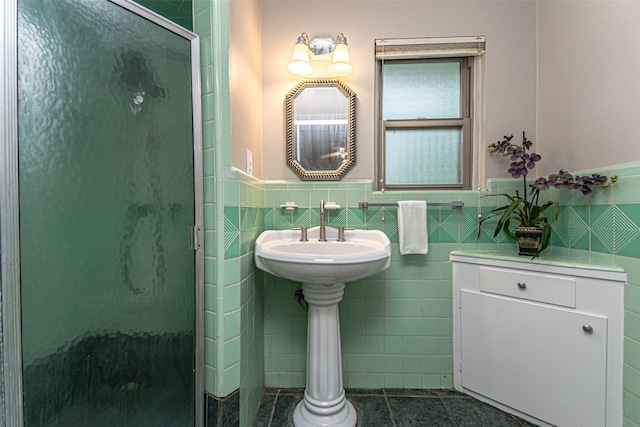 bathroom featuring tile patterned flooring, a shower with door, and tile walls