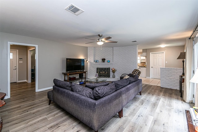 living room featuring a fireplace, light hardwood / wood-style floors, and ceiling fan