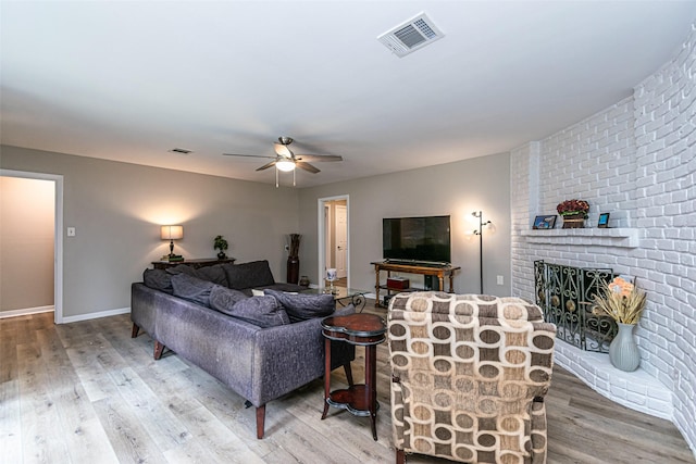 living room with a fireplace, wood-type flooring, and ceiling fan