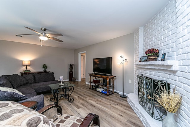 living room featuring a fireplace, light wood-type flooring, and ceiling fan