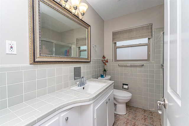 bathroom with vanity, toilet, tile walls, and a shower with shower door