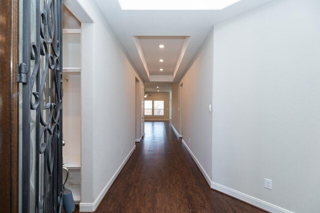 hallway with dark wood-type flooring and a raised ceiling