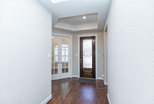 foyer with dark hardwood / wood-style flooring, a raised ceiling, and french doors