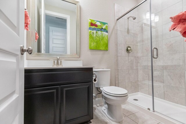 bathroom featuring toilet, tile patterned floors, a shower with shower door, and vanity