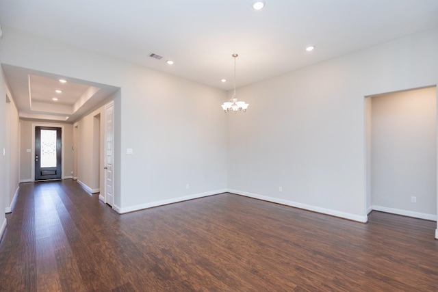 empty room featuring dark hardwood / wood-style floors and a notable chandelier