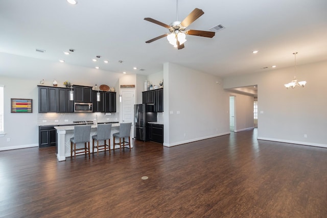 kitchen featuring a kitchen bar, black refrigerator, dark hardwood / wood-style floors, and a center island with sink