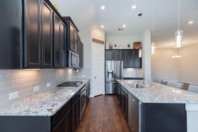 kitchen featuring dark hardwood / wood-style floors, pendant lighting, sink, a kitchen island with sink, and stainless steel appliances