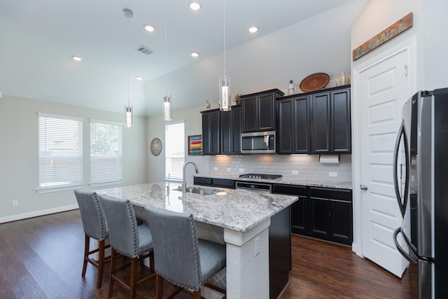 kitchen featuring decorative light fixtures, lofted ceiling, sink, a kitchen island with sink, and stainless steel appliances