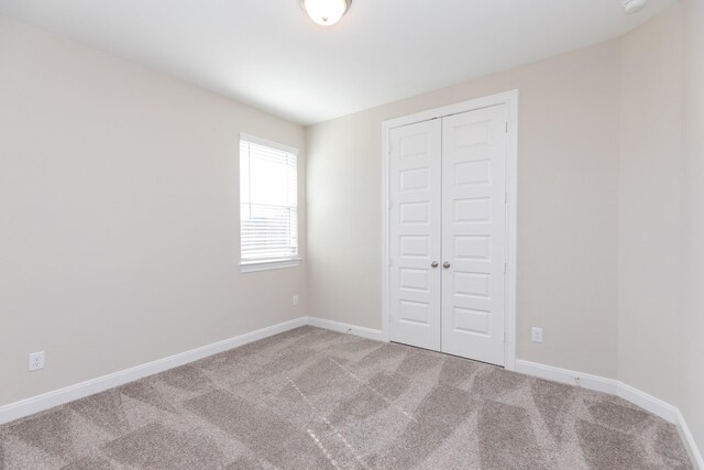 unfurnished bedroom with light colored carpet and a closet