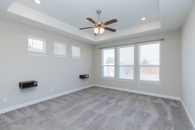 carpeted spare room featuring a raised ceiling and ceiling fan