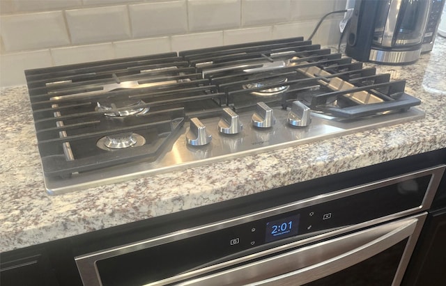 interior details with stainless steel appliances, light stone countertops, and decorative backsplash