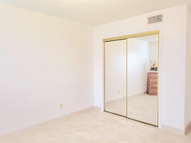 unfurnished bedroom with a textured ceiling and a closet