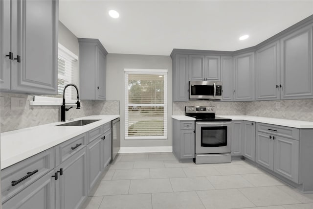 kitchen featuring appliances with stainless steel finishes, gray cabinets, a healthy amount of sunlight, and sink