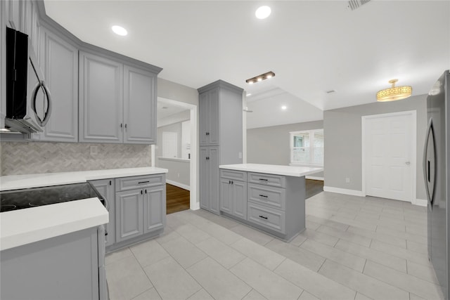 kitchen featuring gray cabinets, stainless steel fridge, light tile patterned floors, and decorative backsplash