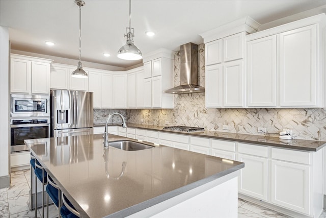 kitchen featuring sink, an island with sink, wall chimney range hood, and appliances with stainless steel finishes