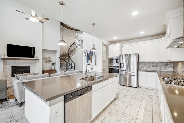 kitchen with white cabinets, appliances with stainless steel finishes, a kitchen island with sink, and sink