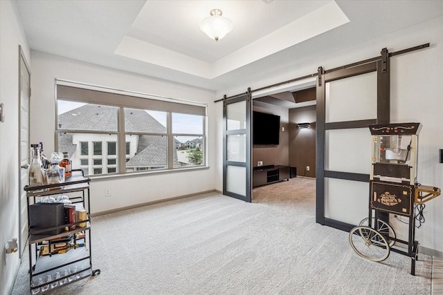 carpeted living room featuring a tray ceiling and a barn door