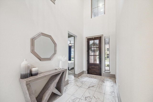 foyer entrance with ceiling fan and a high ceiling