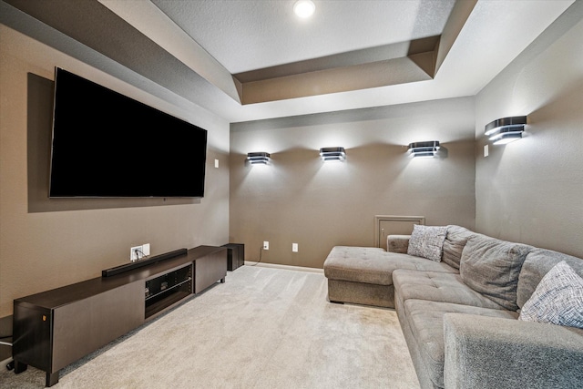 home theater room with a raised ceiling and light carpet