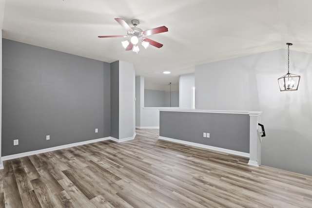 empty room with hardwood / wood-style flooring and ceiling fan with notable chandelier