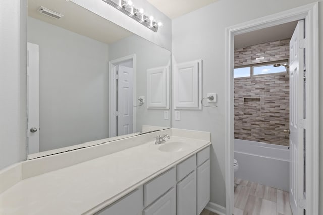 full bathroom with vanity, tiled shower / bath, and toilet