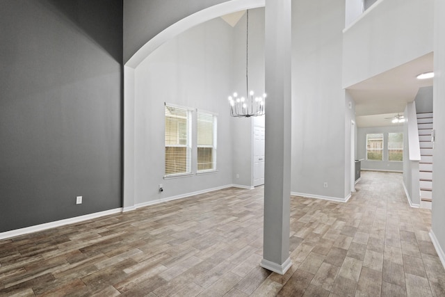 interior space with hardwood / wood-style flooring, a towering ceiling, and ceiling fan with notable chandelier