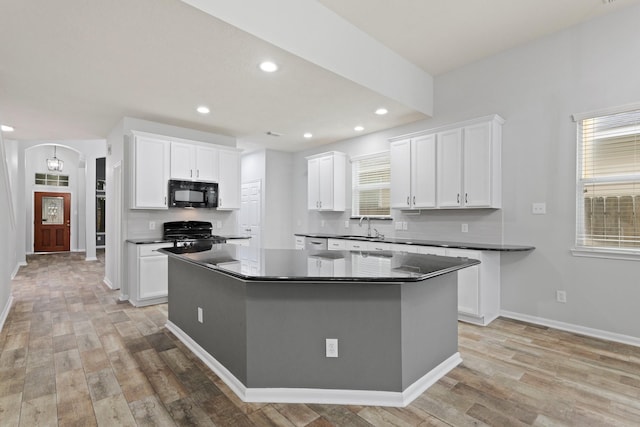 kitchen featuring sink, white cabinetry, black appliances, a kitchen island, and light wood-type flooring