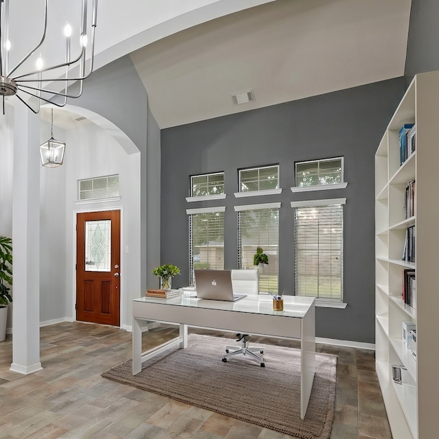 office area with hardwood / wood-style floors, a chandelier, and a high ceiling