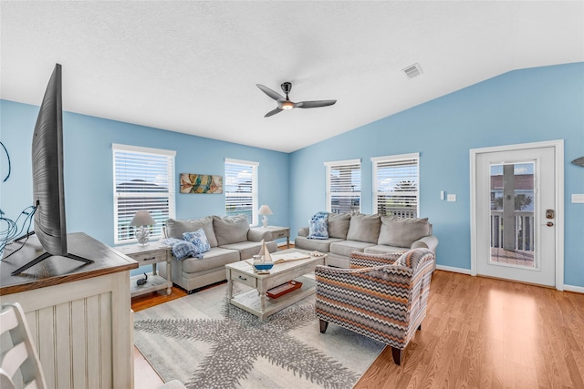 living room with ceiling fan, light hardwood / wood-style flooring, and vaulted ceiling