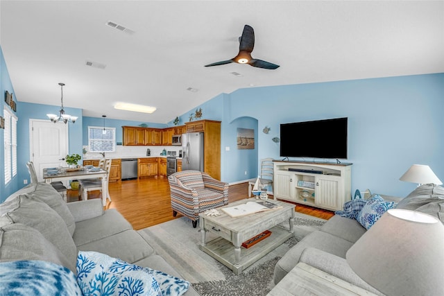 living room with light hardwood / wood-style flooring, vaulted ceiling, and ceiling fan with notable chandelier