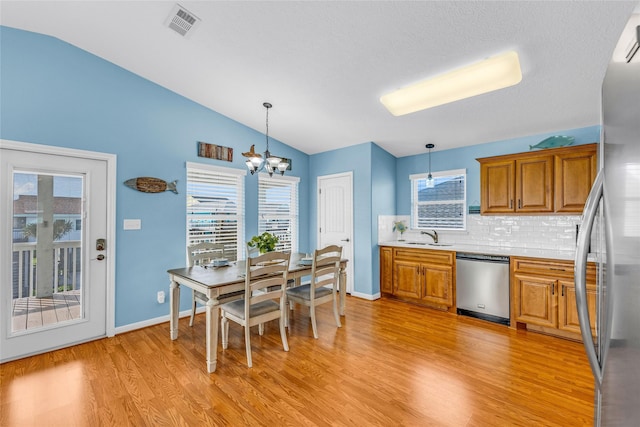 kitchen with a chandelier, tasteful backsplash, hanging light fixtures, and appliances with stainless steel finishes