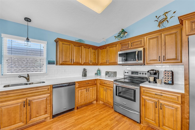 kitchen featuring vaulted ceiling, hanging light fixtures, stainless steel appliances, tasteful backsplash, and sink