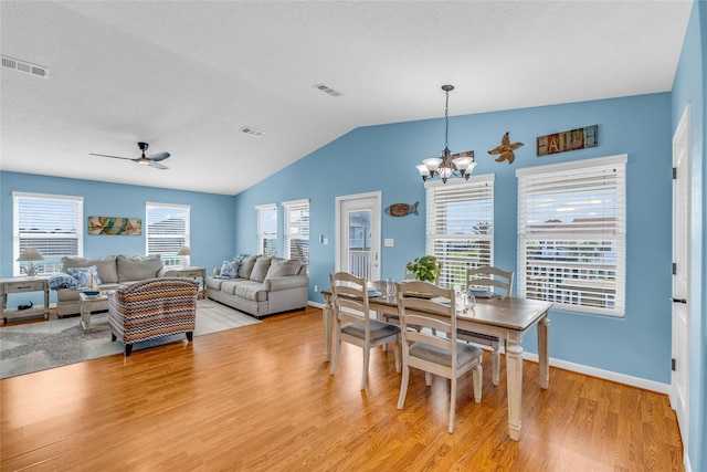 dining space featuring ceiling fan with notable chandelier, vaulted ceiling, and light hardwood / wood-style floors