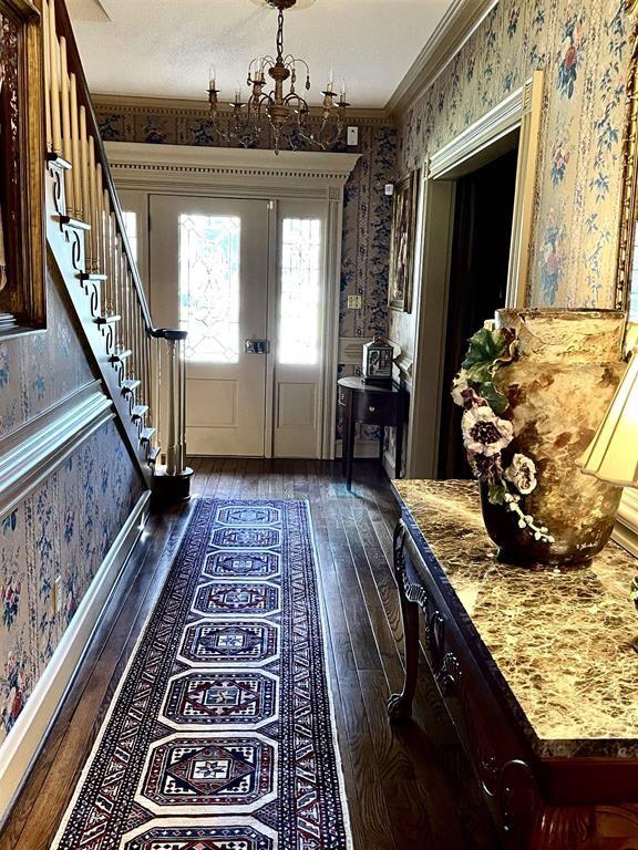 foyer with a chandelier, dark hardwood / wood-style flooring, and ornamental molding