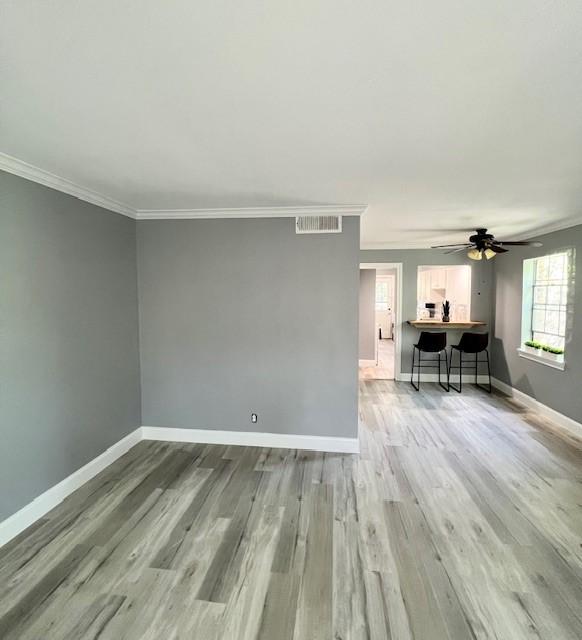 empty room featuring ceiling fan, light hardwood / wood-style flooring, and ornamental molding